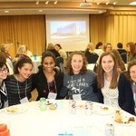 A group of women smile at dinner